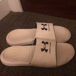A pair of white and black Under Armour Slides